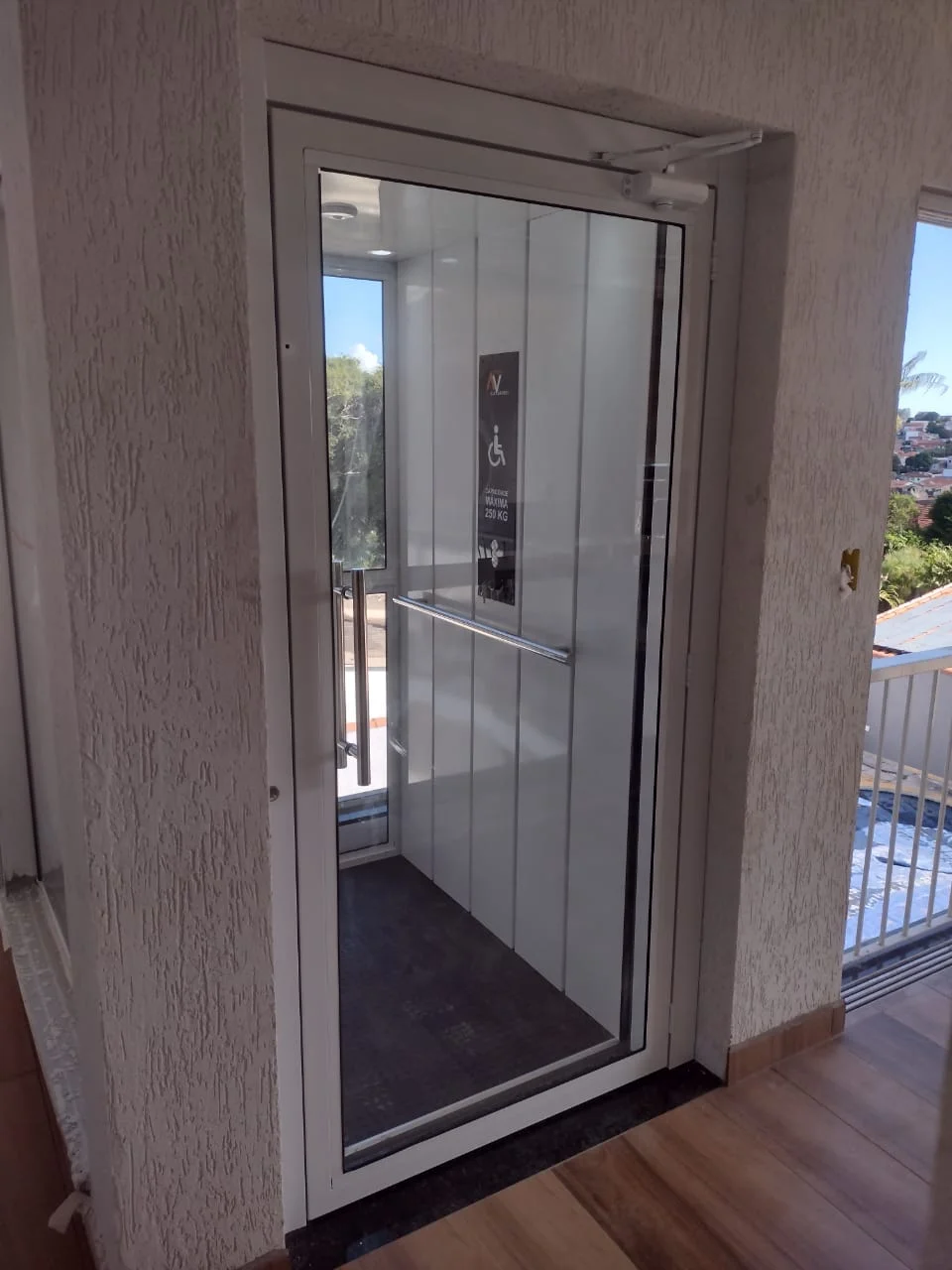 Elevador residencial com porta de vidro instalado em varanda